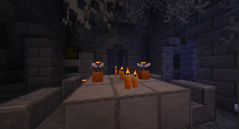 A room in the creaking crypt with a table, potted eyeblossoms, and some candles